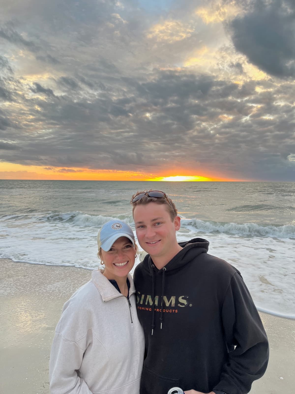 Allie and Chris on the beach as the sun sets over the water