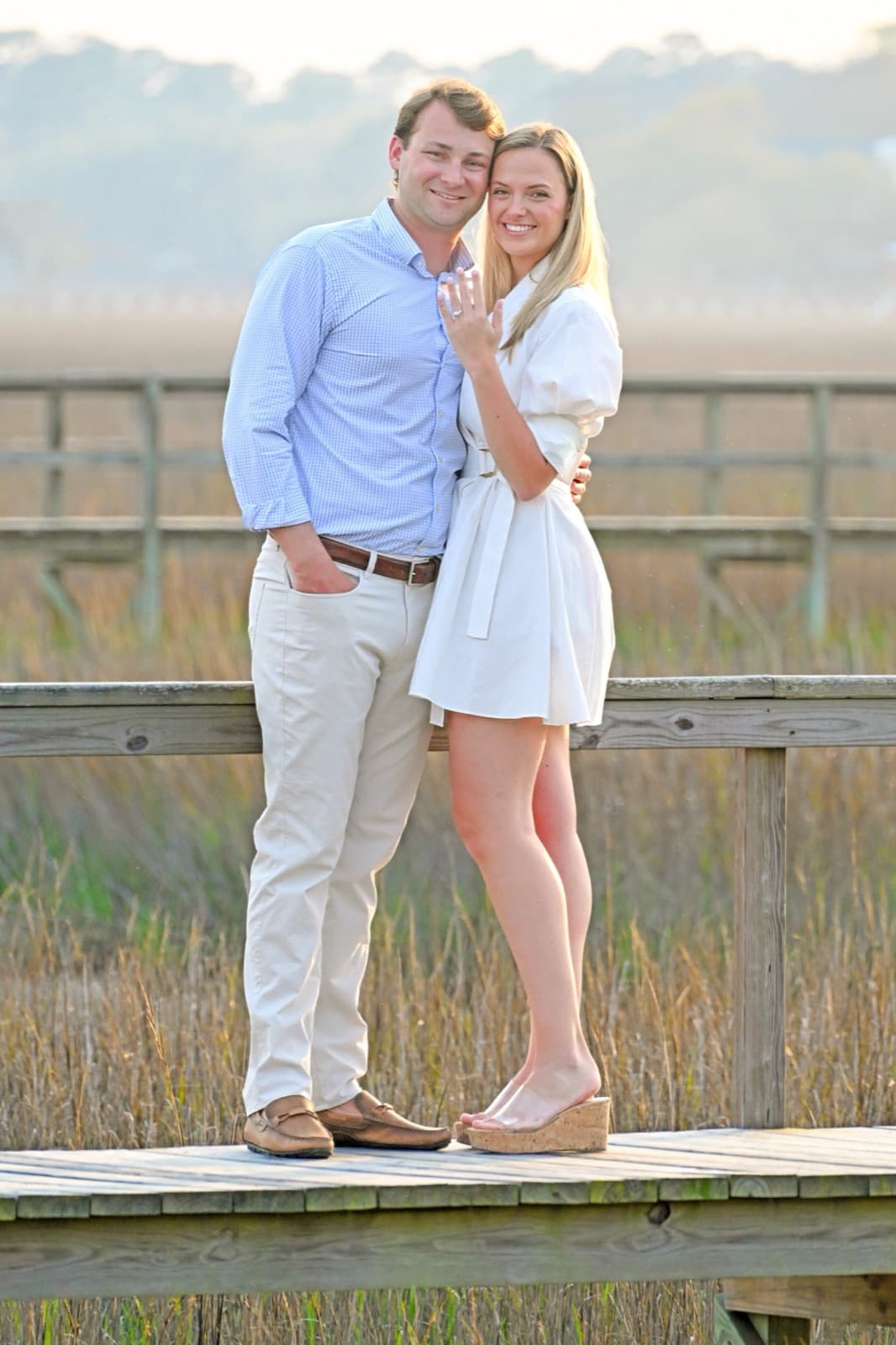 Allie and Chris on a marsh boardwalk, Allie showing her ring