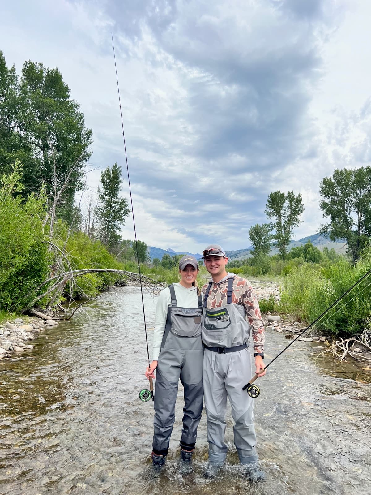 Allie and Chris in waders, fly fishing in a mountain river