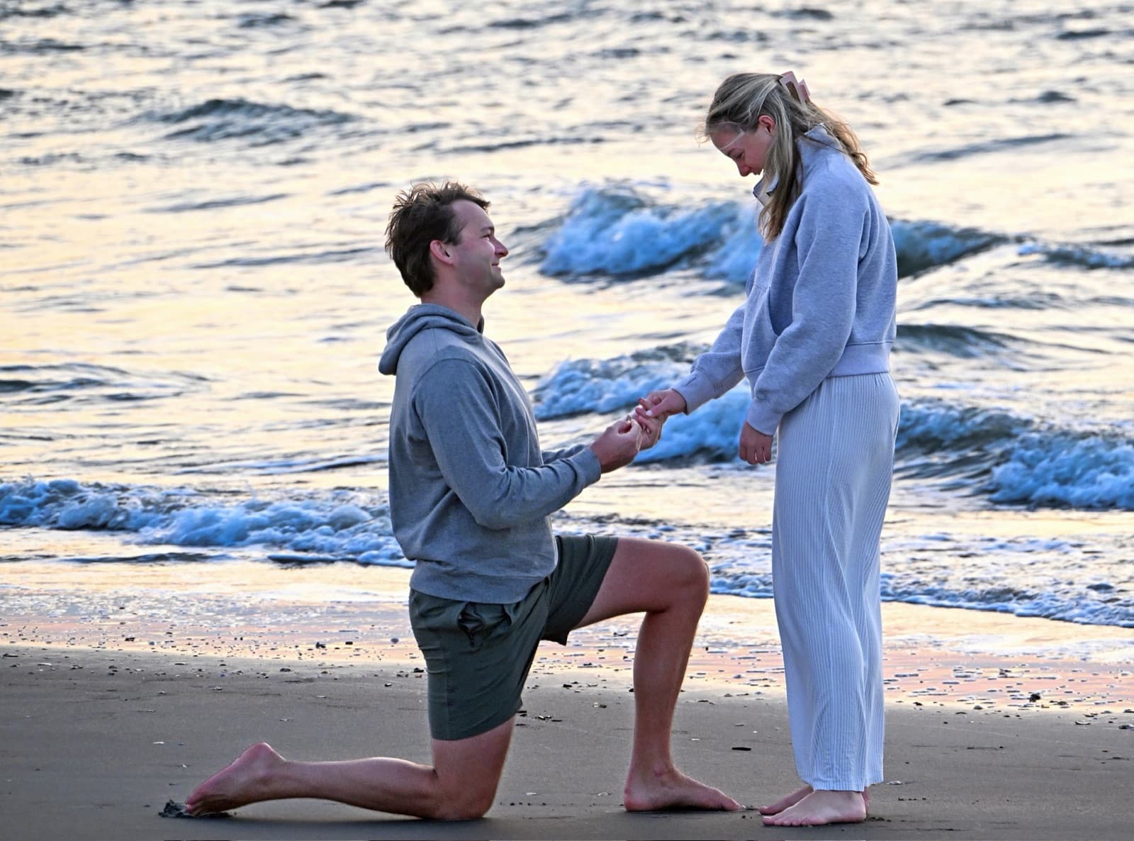 Chris on one knee proposing to Allie on the beach at sunrise